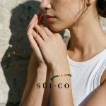 Model wearing Sui Artisan Esme emerald czech crystal bracelet with gold chain extender